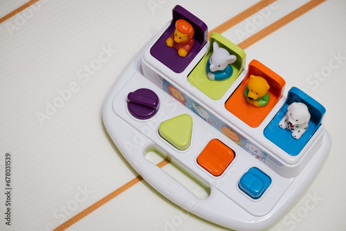 Kids pop up toy on playmat with buttons that help with motor skills development and stimulation for babies and toddlers. Colour toy with shapes, colours and animals for motor skills and engagement 