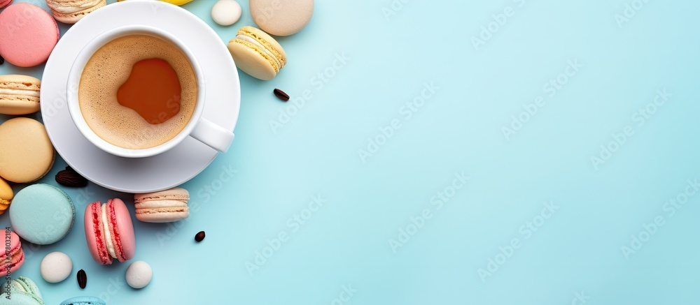 Colorful macarons and a coffee cup on a pastel blue background in a top view Cozy breakfast Fashionable flat lay with sweet treats Copy space image Place for adding text or design - obrazy, fototapety, plakaty 