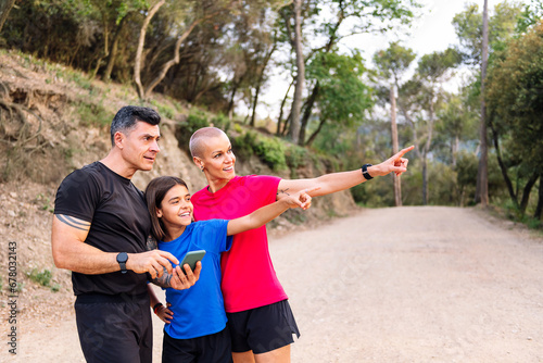 sporty family using a mobile phone to decide the route of their trail running training, concept of sport with kids in nature and active lifestyle © Raul Mellado