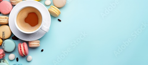 Colorful macarons and a coffee cup on a pastel blue background in a top view Cozy breakfast Fashionable flat lay with sweet treats Copy space image Place for adding text or design