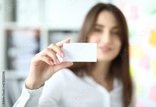 Focus on tender hand of smiling businesswoman showing special blank business card to friendly colleague or partner. Copy space on biz pasteboard. Blurred background