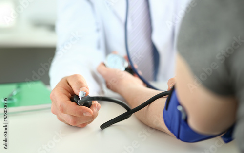 Close-up of worried patient sitting next to professional therapist. Specialist performing common procedure to find out the state man's health. Medical treatment concept