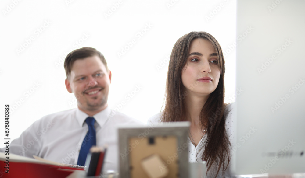 Portrait of designers sitting in modern workplace and looking at something. Gorgeous woman in trendy white blouse discussing art project with colleague. Blurred background Portrait of designers sitting in modern workplace and looking at something. Gorgeous woman in trendy white blouse discussing art project with colleague. Blurred background