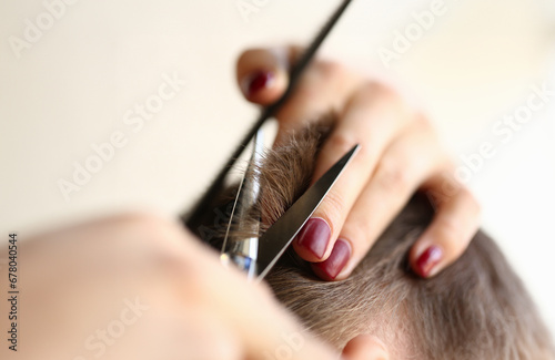 Female Hands Cutting Brown Hair with Scissors. Professional Hairdresser Making Haircut. Woman Fingers Trimming Male Hairdo. Woman Stylist with Manicure Holding Tool for Hairstyling Close-up Photo