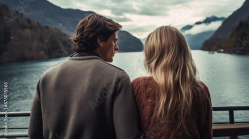 Back view of couple that is standing and looking at a lake in the mountains © standret