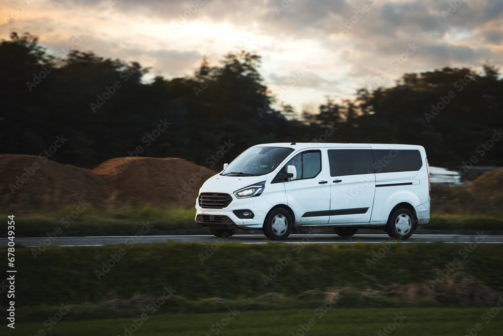 Fast-Moving White Delivery Van on Urban Highway. Distribution and Logistics in Action. Modern Delivery Van on the Road. Shipping and distribution concept. Fast-Moving White Delivery Van on Urban Highway. Distribution and Logistics in Action. Modern Delivery Van on the Road. Shipping and distribution concept.