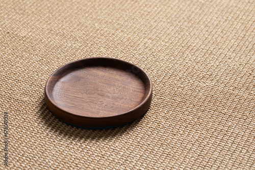 Empty wooden plate. Handmade black walnut wooden plates on sisal rug.
