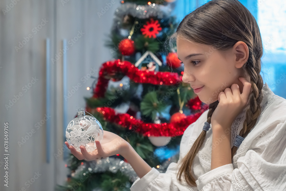 Close-up view of a beautiful girl with romantic braids and a vintage shirt, in a Christmas mood decorates the Christmas tree.