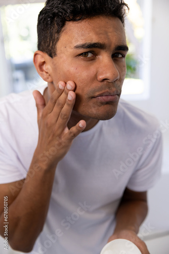 Biracial man applying face cream in bathroom at home