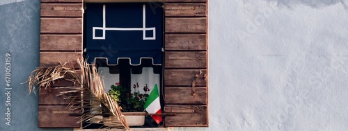 Bello particolare di facciata con serramento e tenda colorata con vaso di fiori e bandiera italiana photo