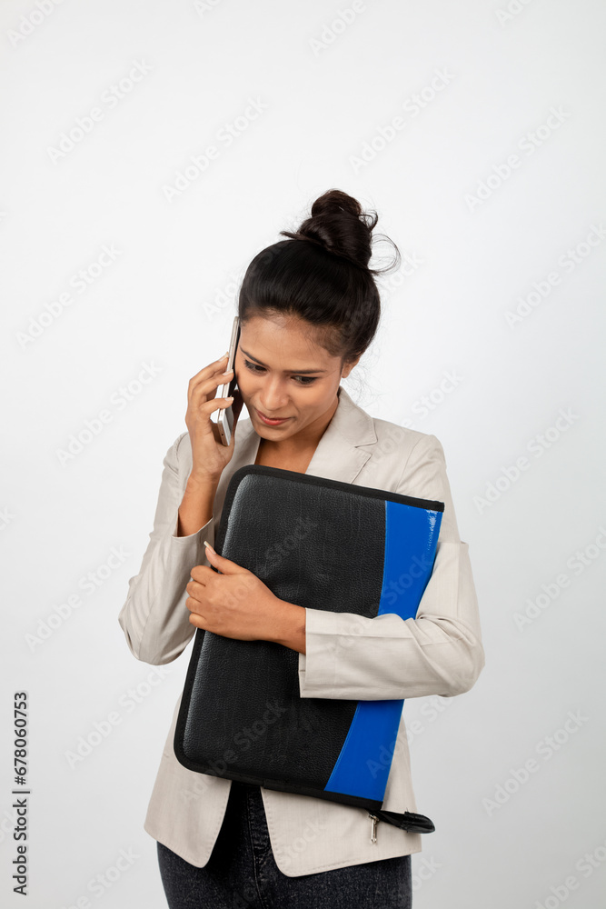 Cheerful corporate office lady holding a folder and a smartphone. Young woman in formal wear wearing white blazer against white background. Cheerful corporate office lady holding a folder and a smartphone. Young woman in formal wear wearing white blazer against white background.