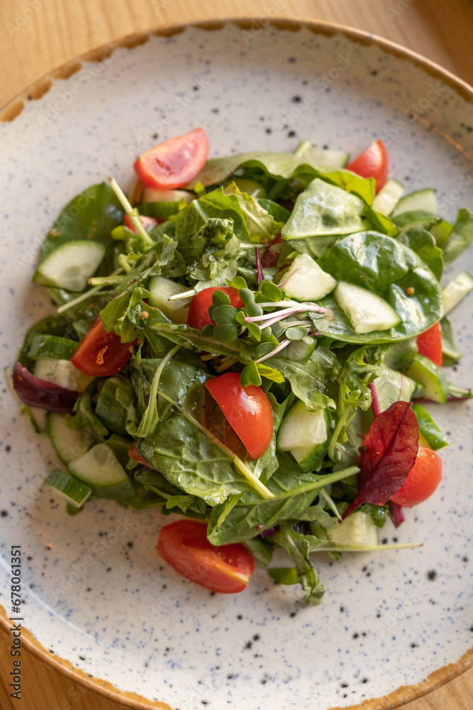 Fresh salad with arugula, cherry tomatoes, cucumbers in a plate close up