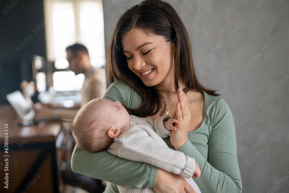 Portrait of a mother hugging and kissing newborn baby. Authentic lifestyle touching tender moment.