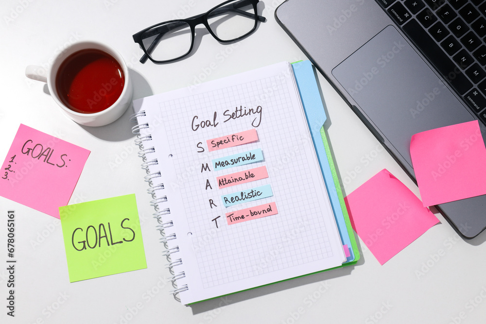 Goal plan in notebook with laptop and tea Goal plan in notebook with laptop and tea
