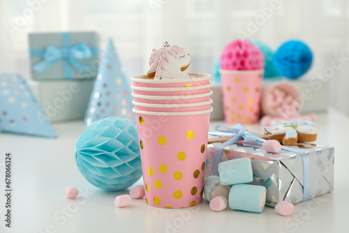 Gift box, paper cups, gingerbread cookies and marshmallows on light background, close up