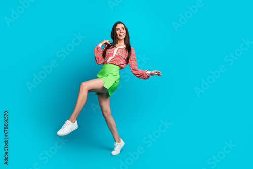 Full length photo of young funny girl walking looking empty space proposition for summer sale isolated on aquamarine color background