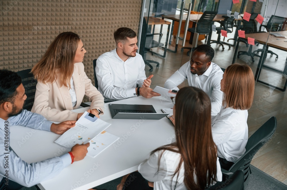 Brainstorming, holding documents, thinking. Group of office workers are together indoors Brainstorming, holding documents, thinking. Group of office workers are together indoors
