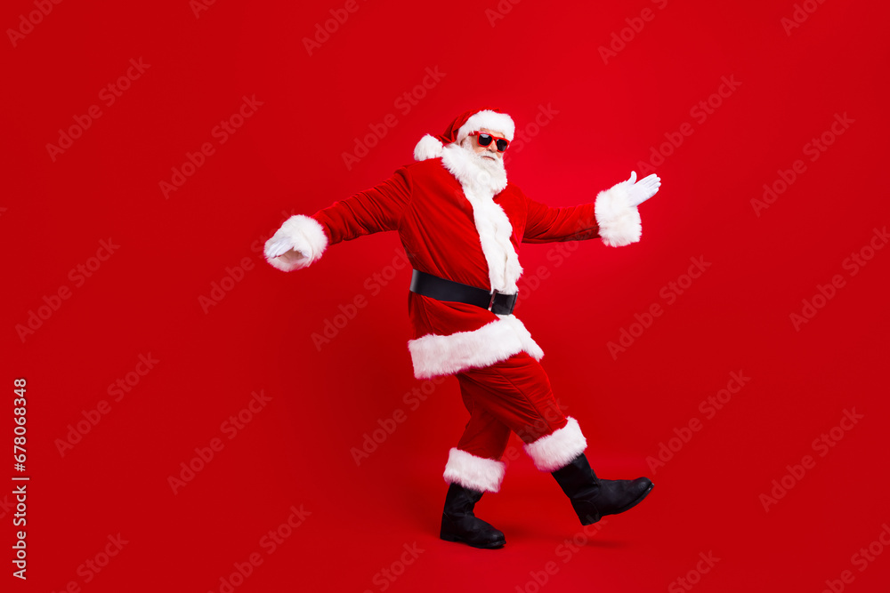 Full size photo of optimistic funky nice grandfather wear santa costume in glasses dancing having fun isolated on red color background Full size photo of optimistic funky nice grandfather wear santa costume in glasses dancing having fun isolated on red color background