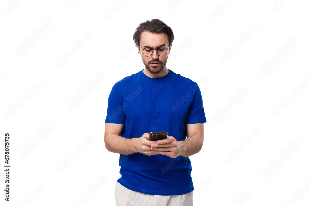 young handsome caucasian man with dark well-groomed hair and beard uses a mobile phone young handsome caucasian man with dark well-groomed hair and beard uses a mobile phone