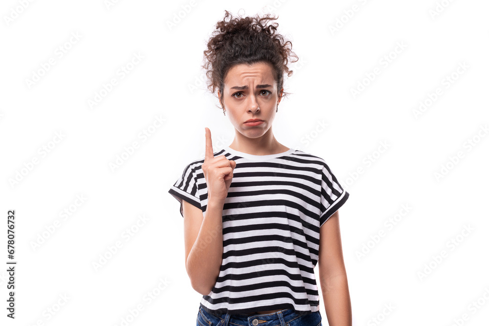 young well-groomed curly woman in a summer t-shirt points her finger on a white background young well-groomed curly woman in a summer t-shirt points her finger on a white background