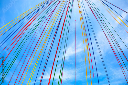 Multicolored ribbons weaves through the sky . Colorful ribbons decoration standing out against the blue sky