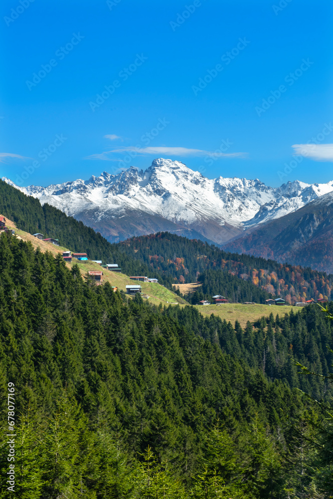 Fototapeta premium Plateau houses made of wood, located in the snowy mountains. Plateau houses are made of stone and wood. Wooden plateau houses built on a hill. Pokut Plateau Rize Türkiye