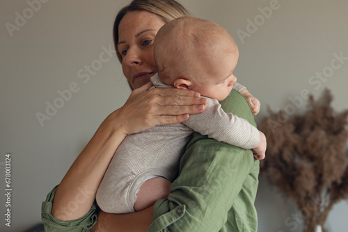 Mother comforting burping baby over shoulder