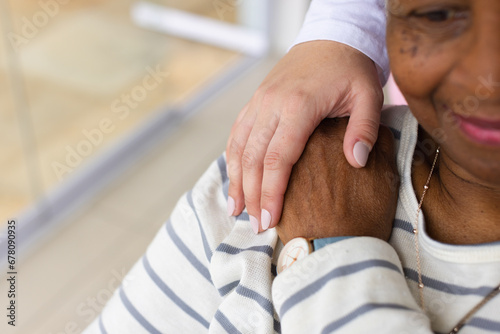 Caucasian female nurse's hand on senior african american woman's shoulder photo