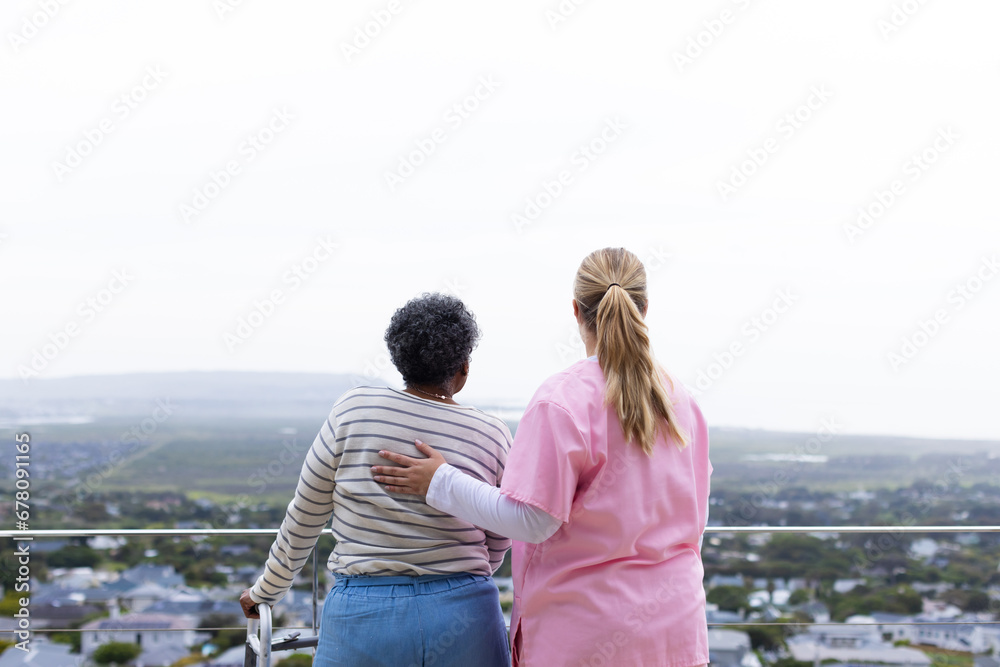 Caucasian female nurse and senior african american female patient on balcony Caucasian female nurse and senior african american female patient on balcony