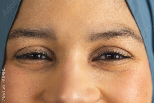 Portrait of happy eyes of biracial woman in hijab at sunny home photo