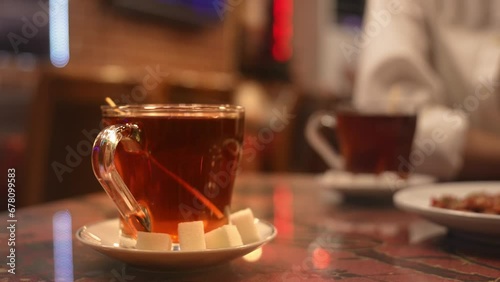 cup of brewed black turkish tea poured from teapot, traditional hot drink concept Attractions in Istanbul in Turkey. Sugar cubes on saucer. photo