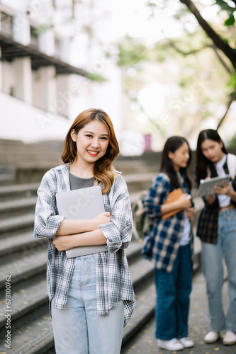 Asian Students are studying the campus park. Young people are spending time together. Reading book, working with laptop, tablet while sitting on stairs