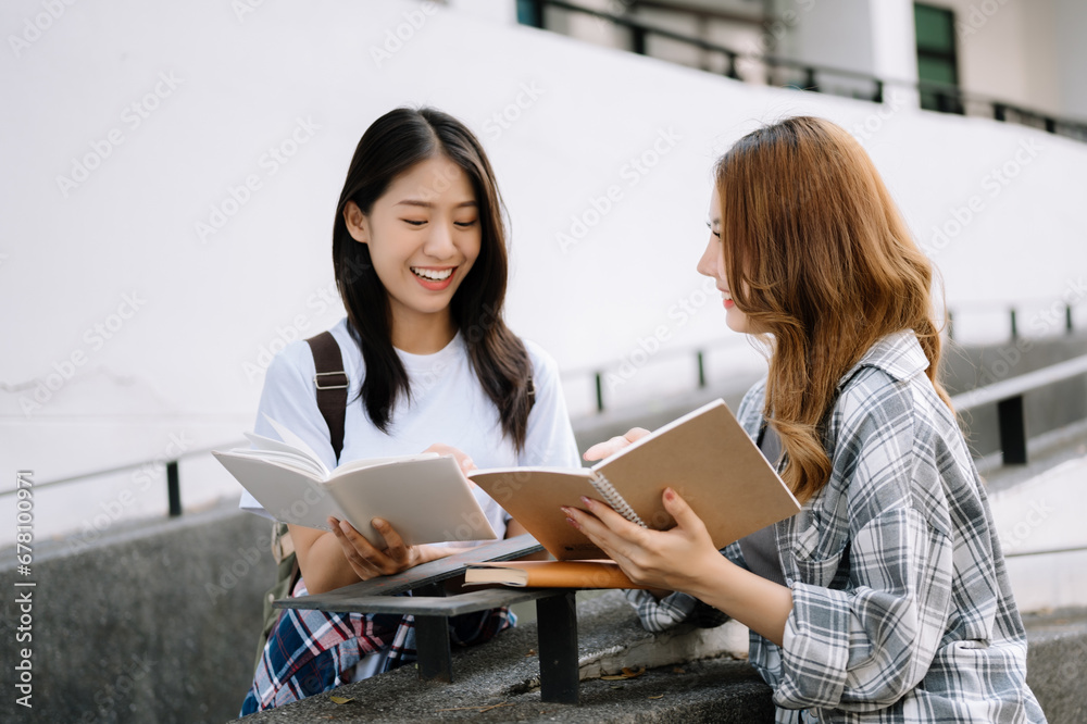 Asian Students are studying the campus park. Young people are spending time together. Reading book, working with laptop, tablet while sitting on stairs Asian Students are studying the campus park. Young people are spending time together. Reading book, working with laptop, tablet while sitting on stairs