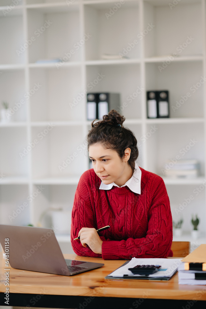 Beautiful woman using laptop and tablet while sitting at her working place. Concentrated ..