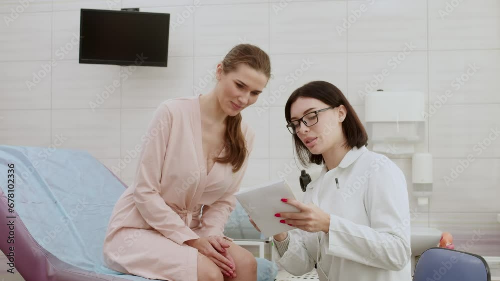 A female patient sits in a gynecological chair during a consultation with the attending gynecologist in a modern clinic after a gynecological examination. Consultations on pregnancy and childbirth. A female patient sits in a gynecological chair during a consultation with the attending gynecologist in a modern clinic after a gynecological examination. Consultations on pregnancy and childbirth.