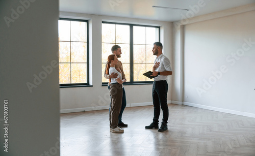 Empty room. Realtor shows an apartment to a young couple