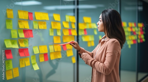 Woman organizer attaches colorful sticky notes to white board. Life hack for easy memorization and reminders of important things in visible place in office. Organization of space and clear schedule photo