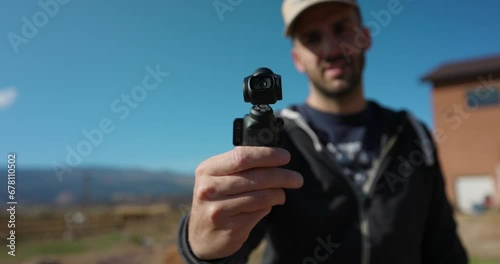 Male Freelancer Holding 3-Axis Stabilized 4K Handheld Camera And Moving Around With Hand. Bokeh Background With Blue Sky. Slow Motion photo