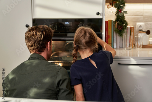 Back view of caucasian father and daughter waiting for homemade cookies