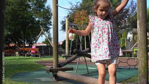 5-year kid girl playing alone outdoors on the eco wooden playground