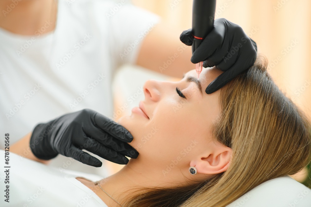 Naklejka premium Process of creating permanent brow makeup with a machine at beauty salon