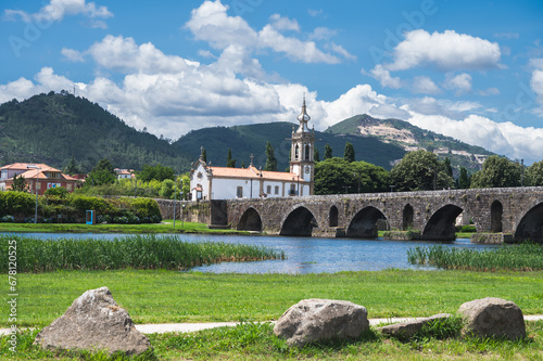 Bridge across the river in Ponte de Lima, southern bank, medieval bridge dates back to 1368, view of the church, river back, mountains or hills on the background, selective focus
