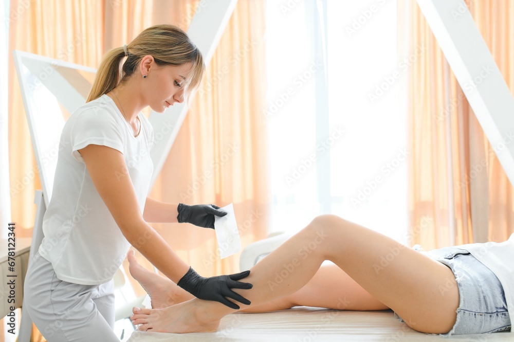 Beautician makes depilation young woman on her feet with wax, liquid sugar Beautician makes depilation young woman on her feet with wax, liquid sugar