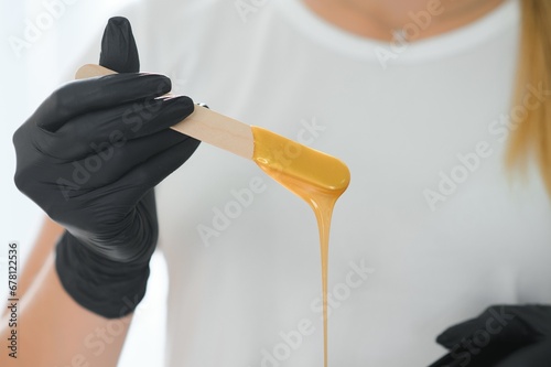 Female cosmetologist holding stick with wax for depilation or sugaring photo