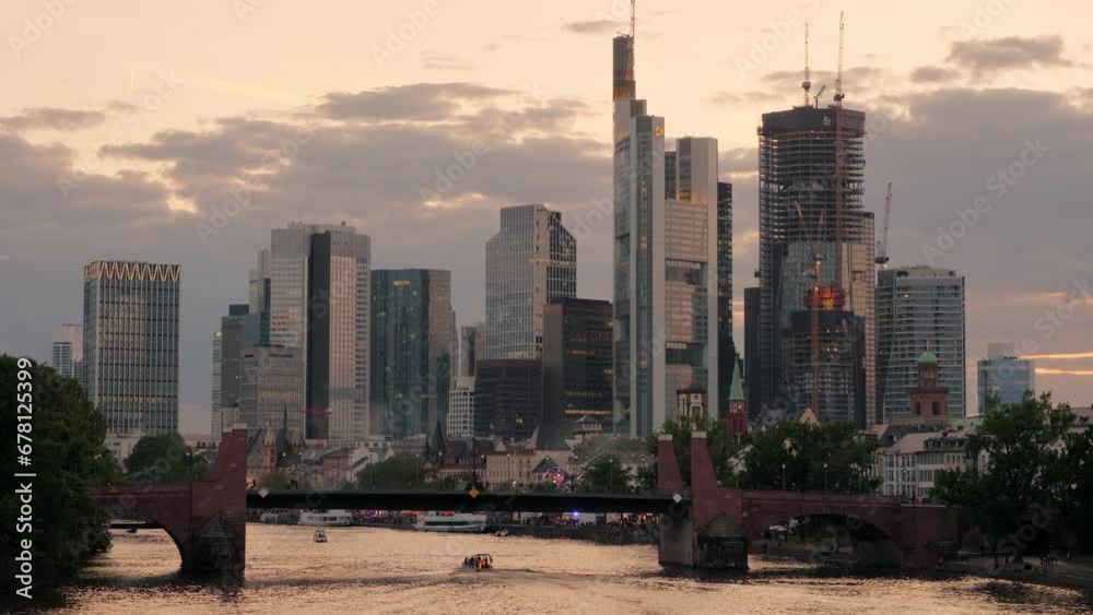 Wide clip of the Frankfurt skyline at sunset taken from Ignatz Bubis Bridge. The city lights are beginning to come on 