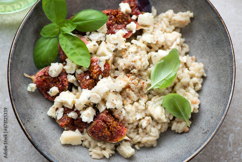 Close-up of risotto with fig fruits, blue cheese and green basil, horizontal shot, selective focus