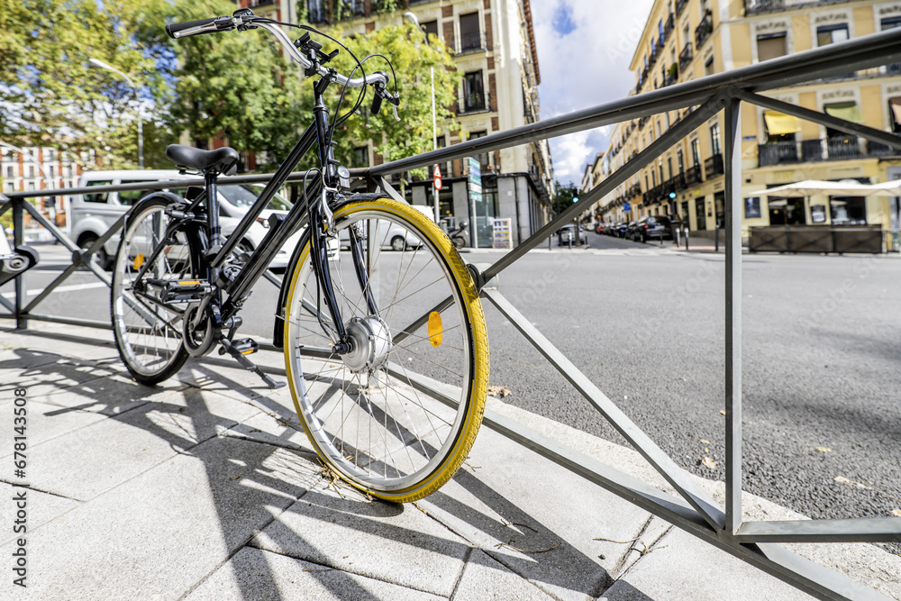 A black touring bicycle with a yellow-covered front wheel