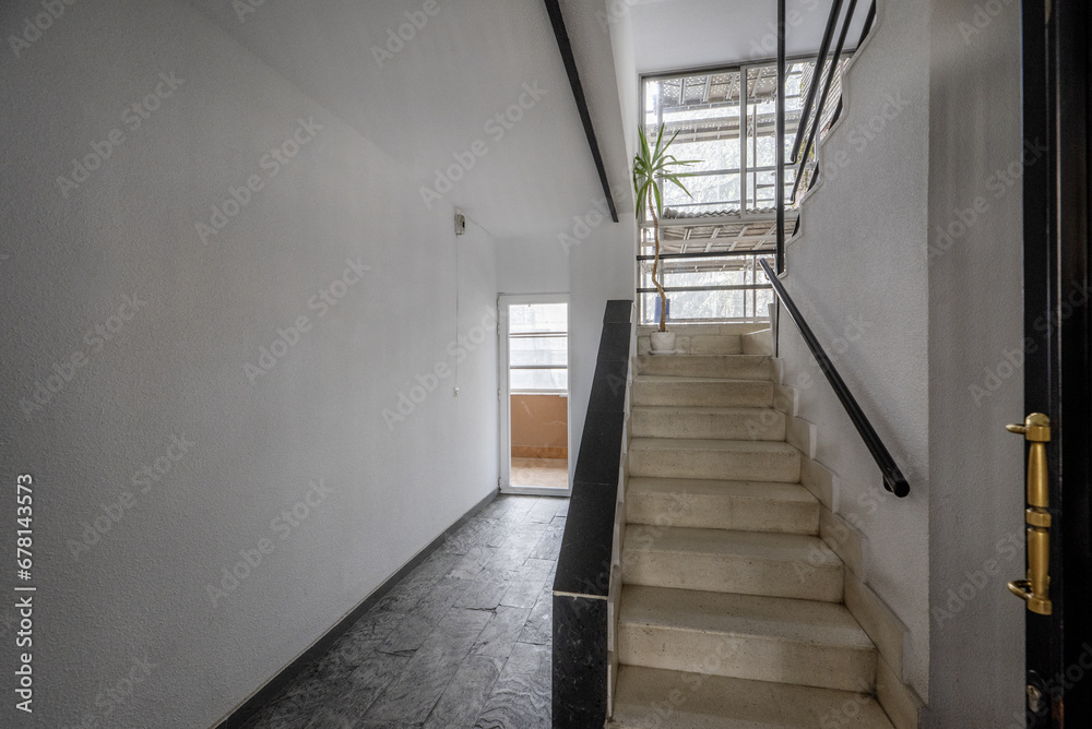 Interior stairs of an urban residential building with access to an interior patio and with scaffolding on the façade