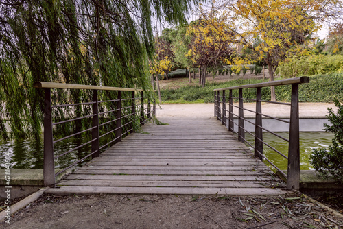 A small bridge made of wooden planks and metal railings over a water channel in an urban park