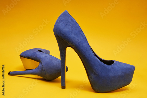 Pair of Blue suede high heel shoes on a yellow background